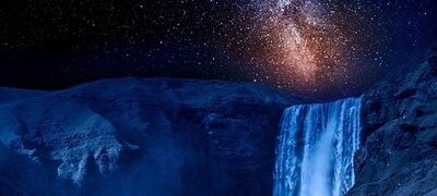 Primer plano de una cascada por la noche con estrellas iluminadas en una galaxia en el cielo